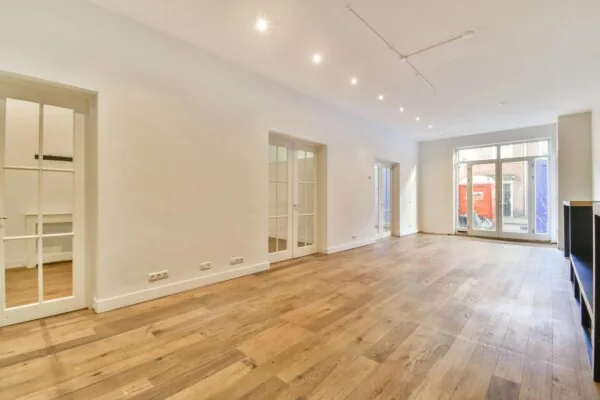 Lichte, ruime woonkamer aan de Korte Schimmelstraat met houten vloer, grote raampartijen en openslaande deuren.